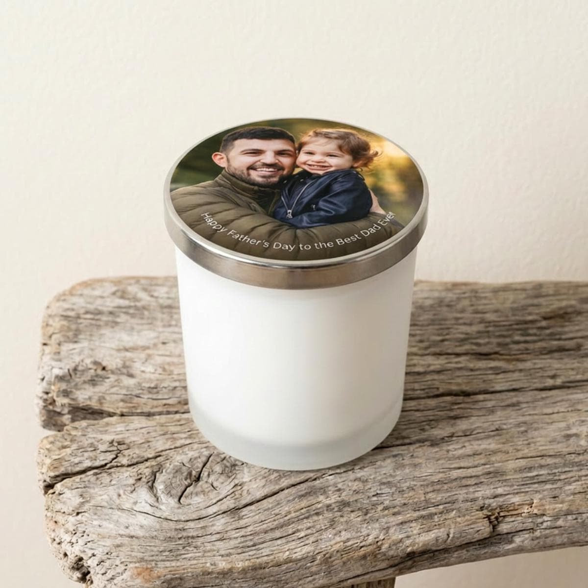 Personalised Fathers Day candle in white frosted glass jar with photo of dad and child printed on the silver-coloured lid, displayed on rustic driftwood.