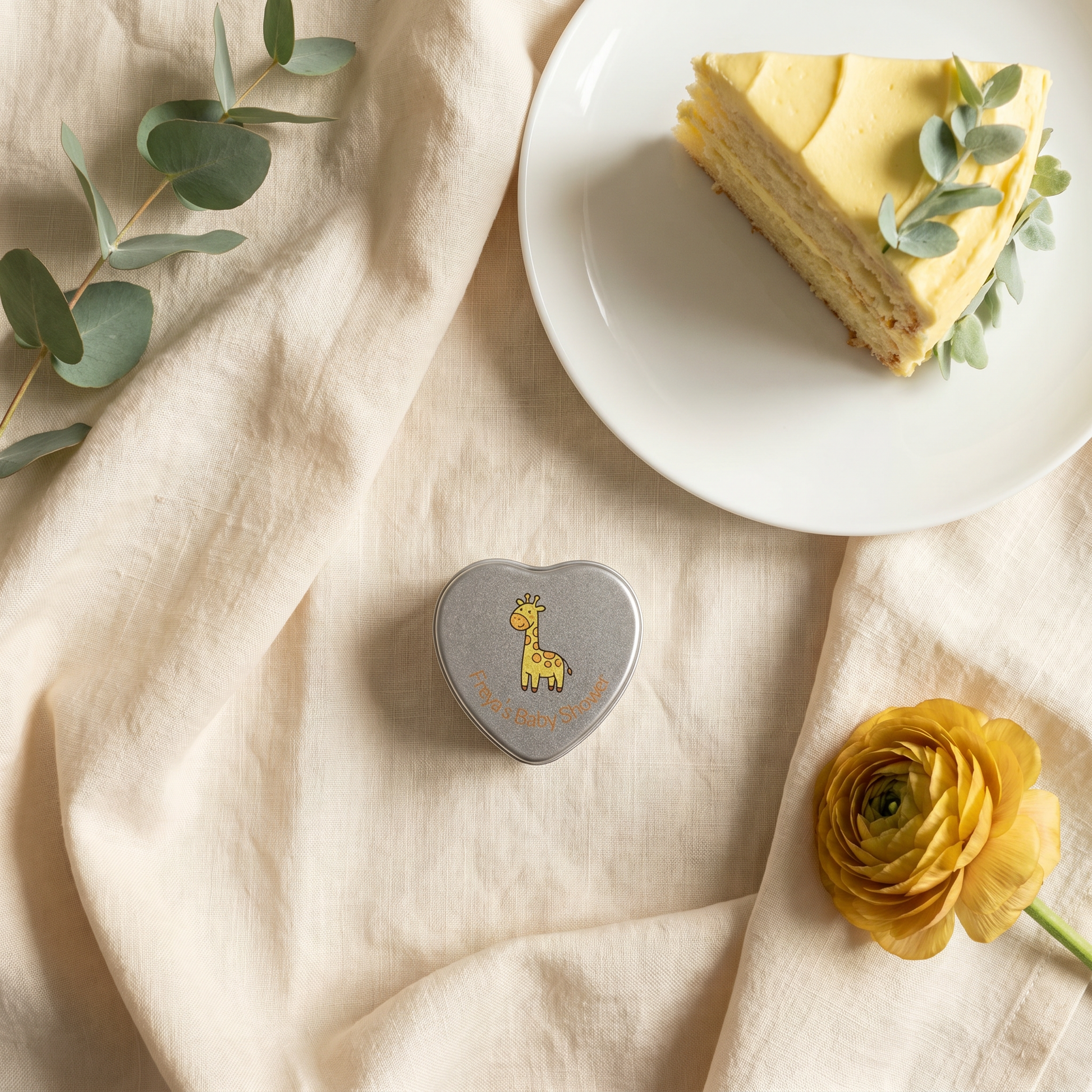 Personalised yellow baby shower heart tin candle favour styled with lemon cake and eucalyptus — giraffe lid design