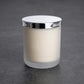 White frosted glass candle jar with silver-coloured lid photographed on a plain grey background.