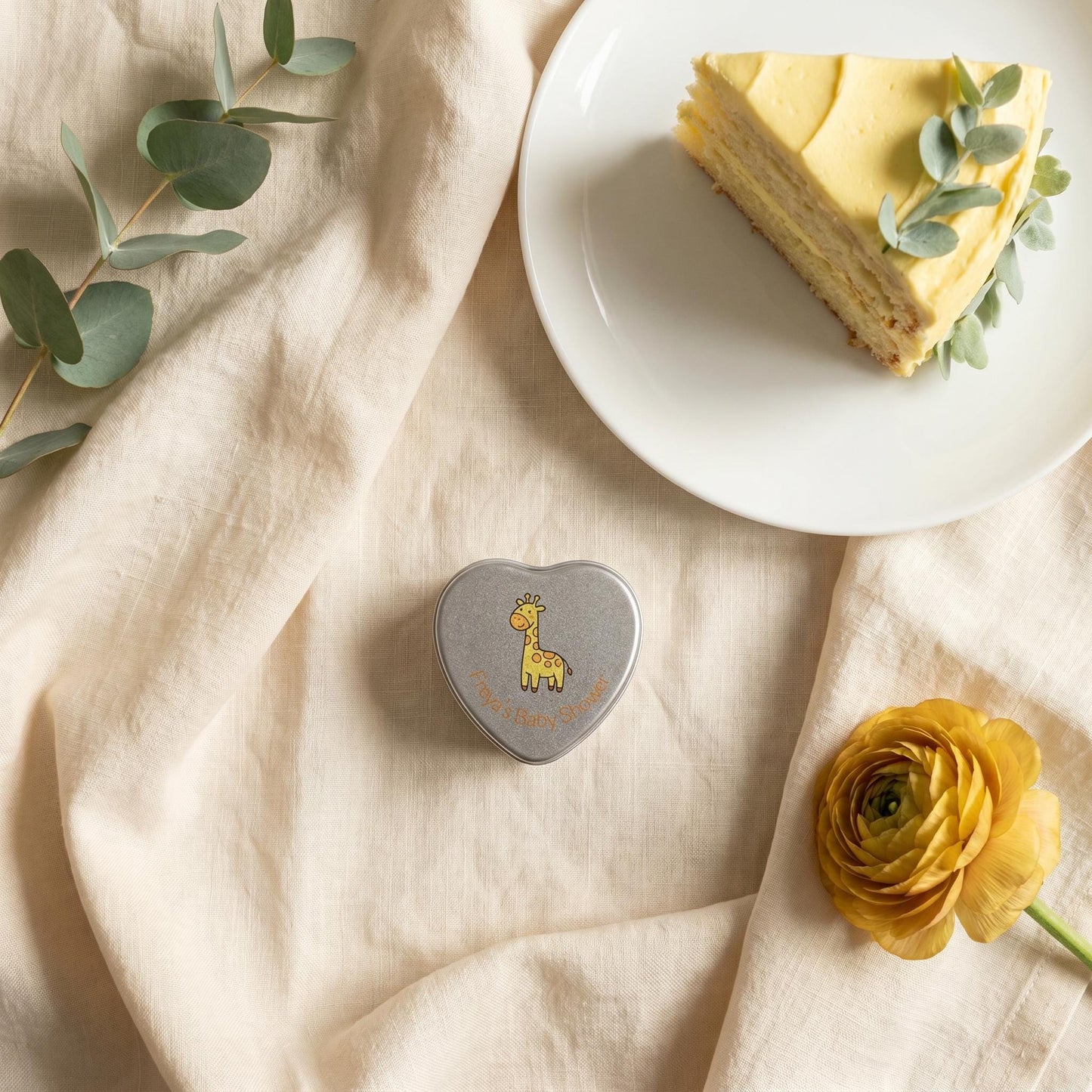 Personalised yellow baby shower heart tin candle favour styled with lemon cake and eucalyptus — giraffe lid design