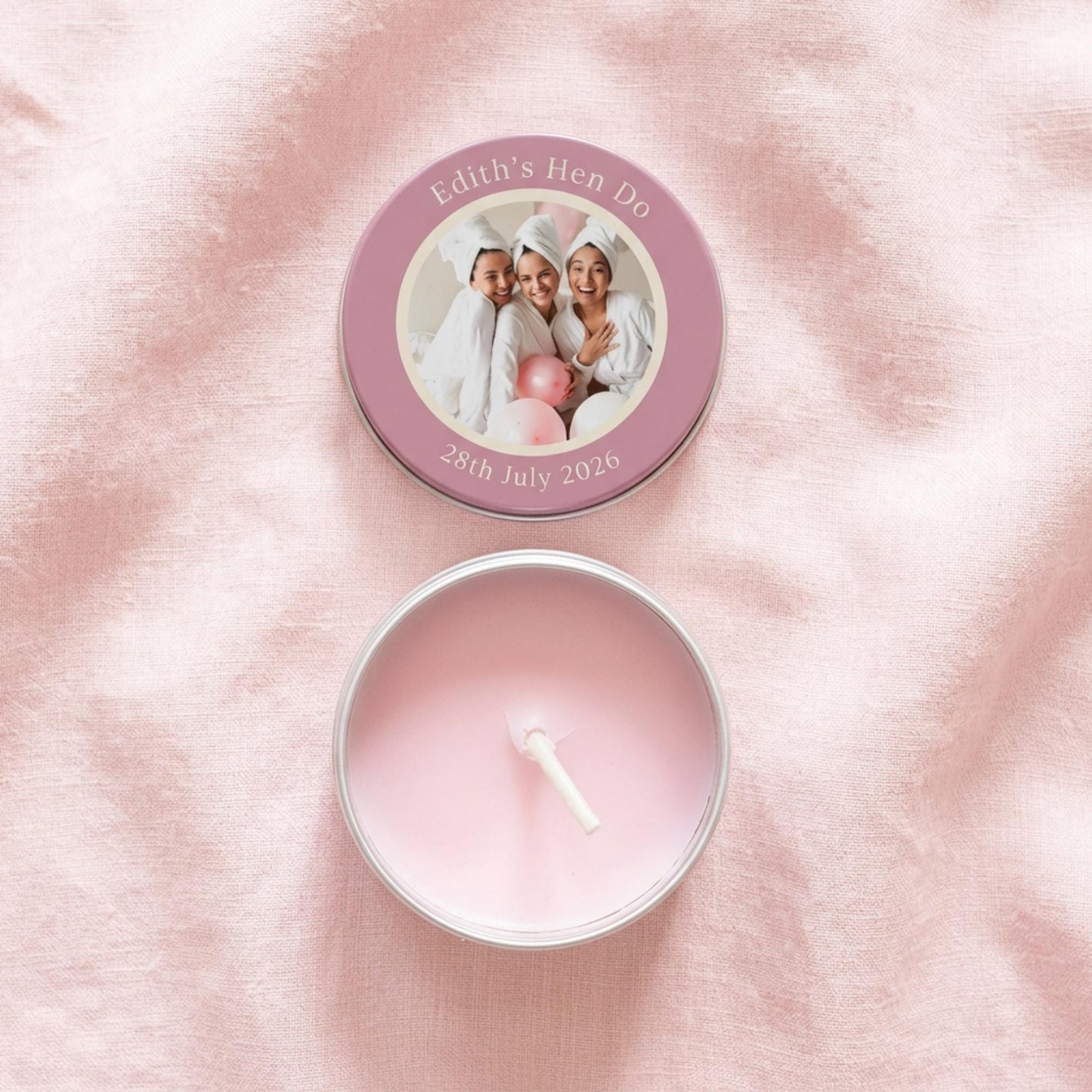 Flat lay of personalised hen party candle tin favour, lid and tin separated showing colour-printed photo design with custom text and date, open tin revealing candle and white cotton wick