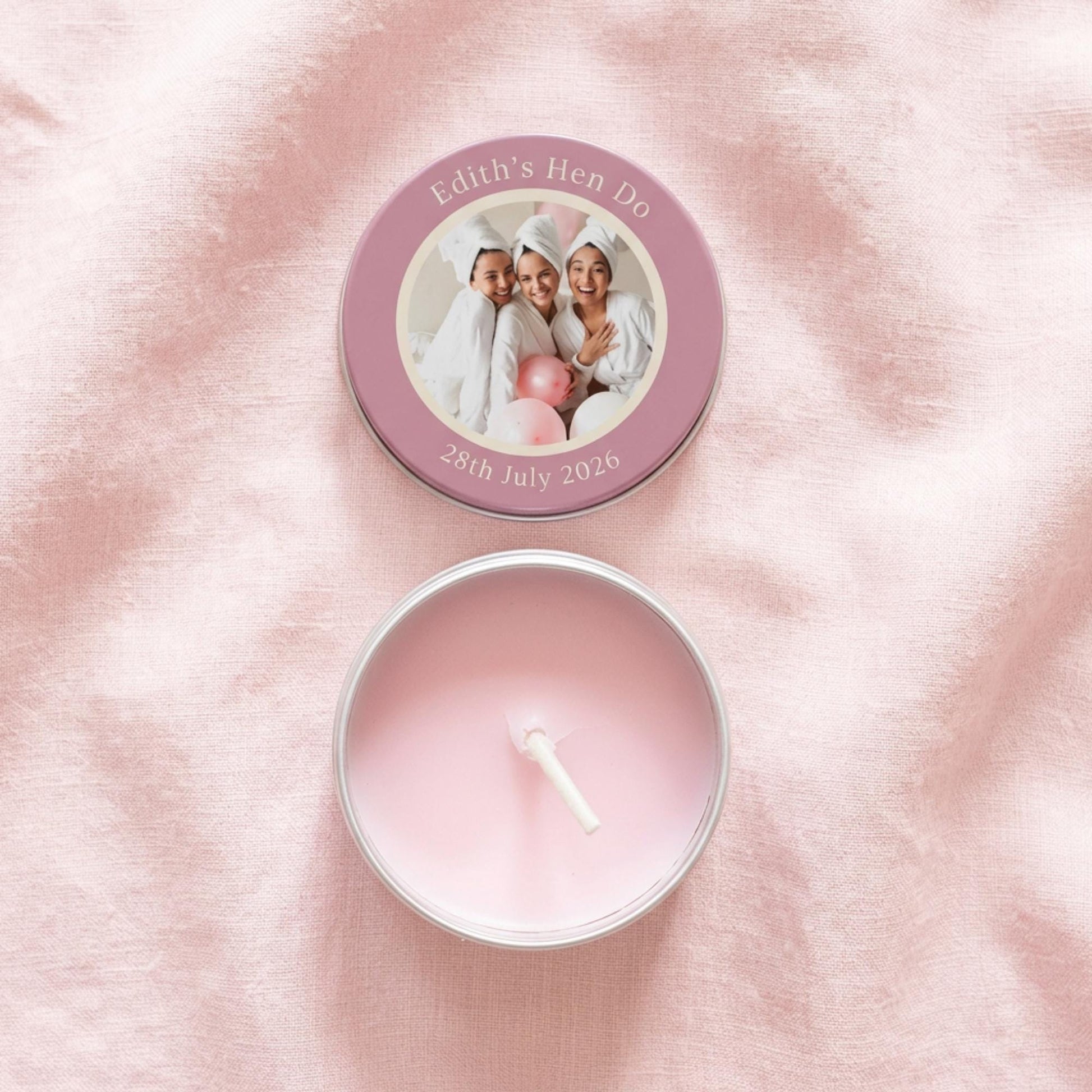 Flat lay of personalised hen party candle tin favour, lid and tin separated showing colour-printed photo design with custom text and date, open tin revealing candle and white cotton wick
