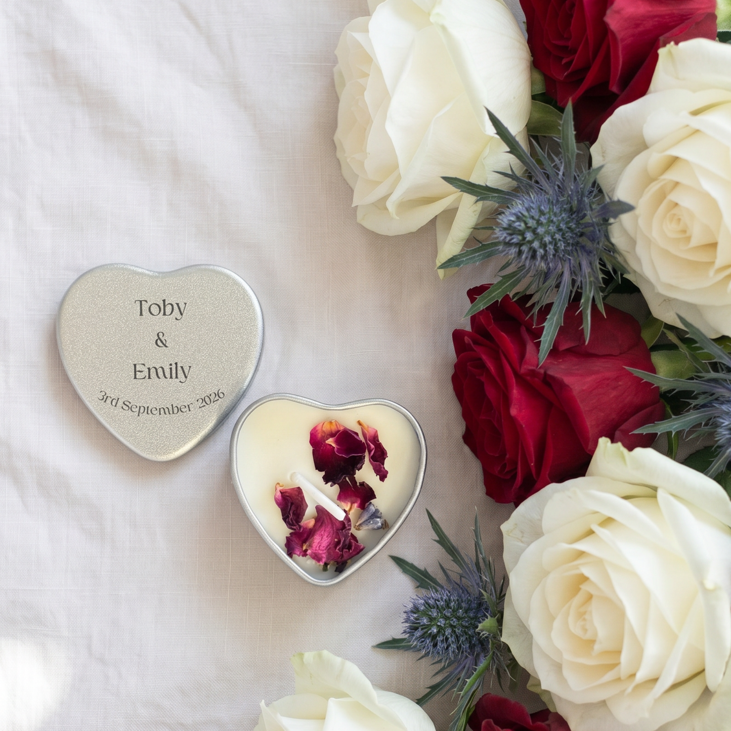 Personalised silver heart tin wedding favour candle with couple's names and date printed on lid, styled with dried botanicals — handmade in the Cotswolds